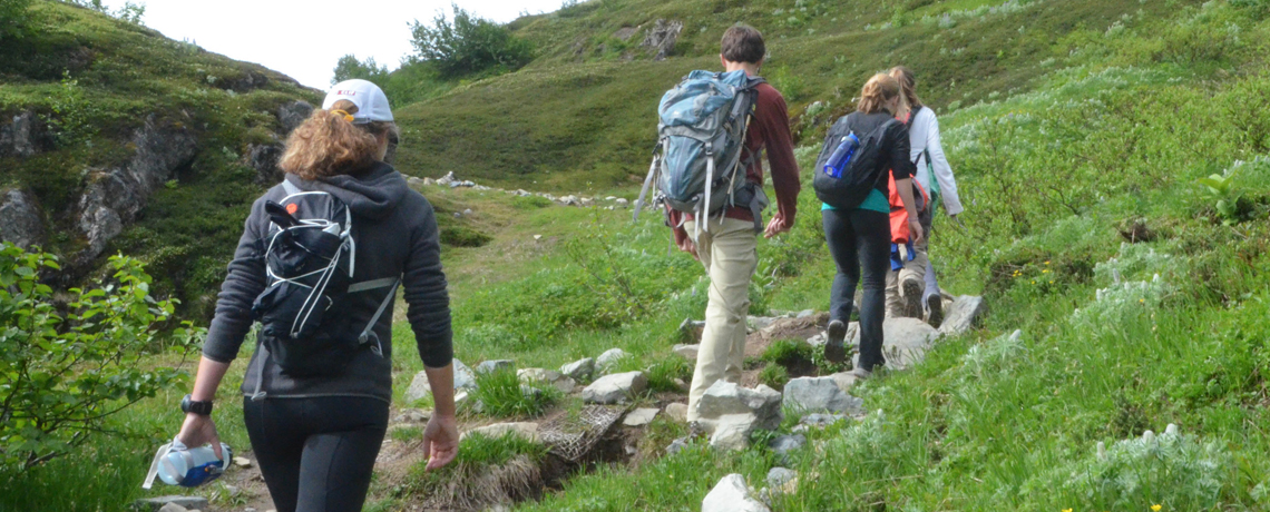 Three young hikers climbing a hill