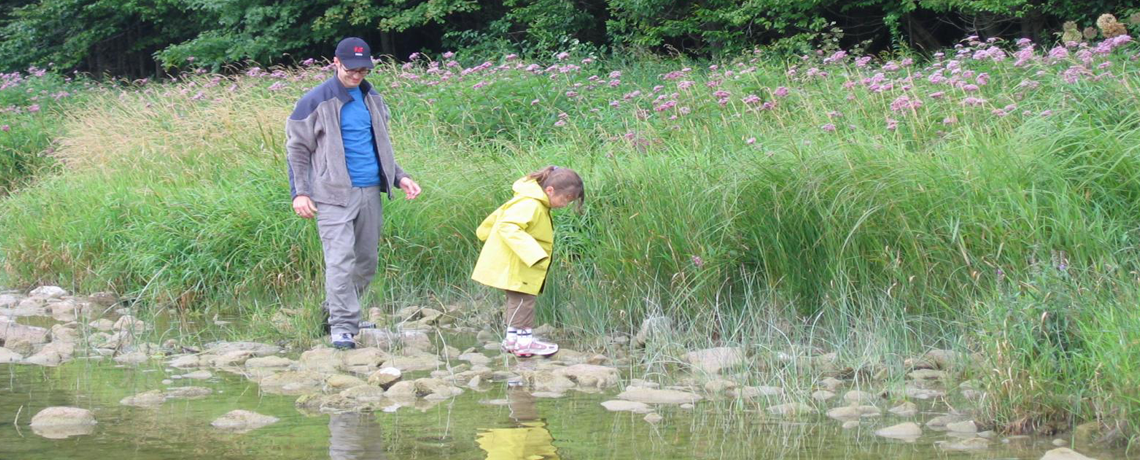Parent and small child exploring a creek